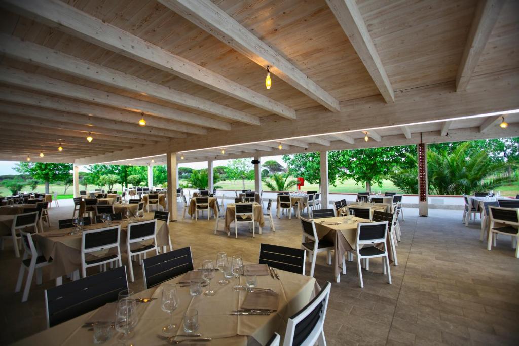 une salle à manger avec tables et chaises et tablesearcher dans l'établissement Resort Abbaia Ba, à Budoni