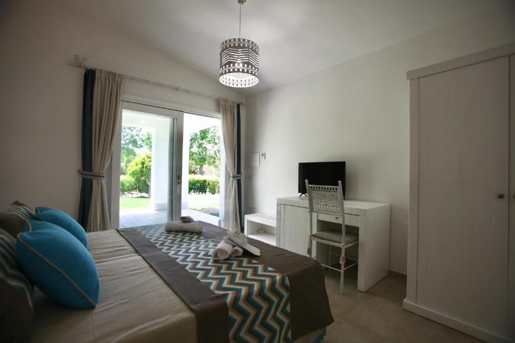 une chambre avec un lit, un bureau et une fenêtre dans l'établissement Resort Abbaia Ba, à Budoni