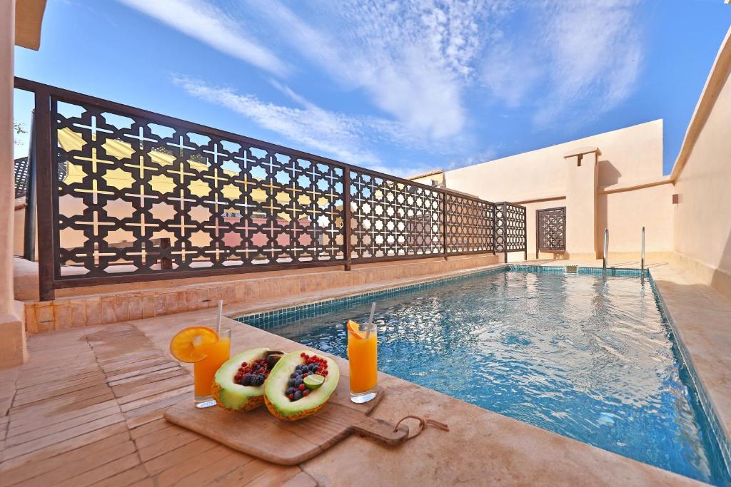 une piscine avec deux beignets et des boissons dans une maison dans l'établissement RIAD THE MILESTONE, à Marrakech
