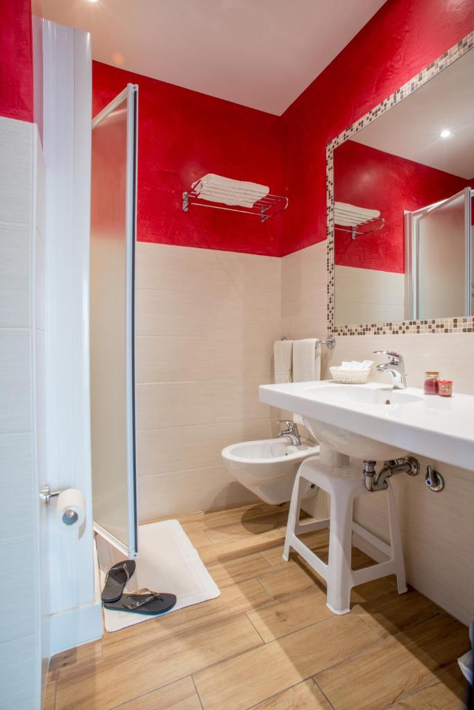 une salle de bain avec un lavabo blanc et des murs rouges dans l'établissement Hotel London, à Cattolica