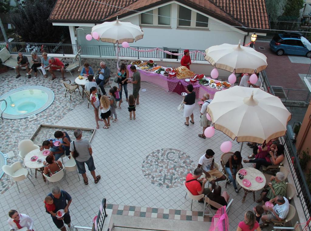 Un groupe de personnes autour d'une table avec des parapluies dans l'établissement Hotel Cannes, à Bellaria-Igea Marina 102 autres photos