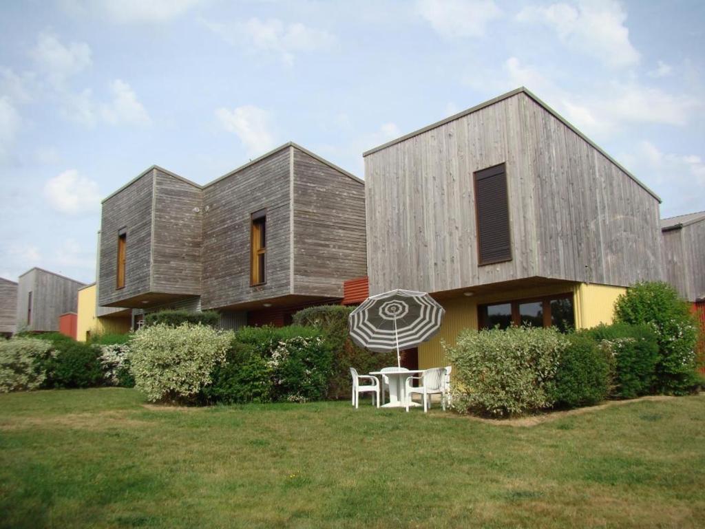 une maison avec une table et un parasol devant elle dans l'établissement Gîte La Chassagne - Gîte n°11, à Videix