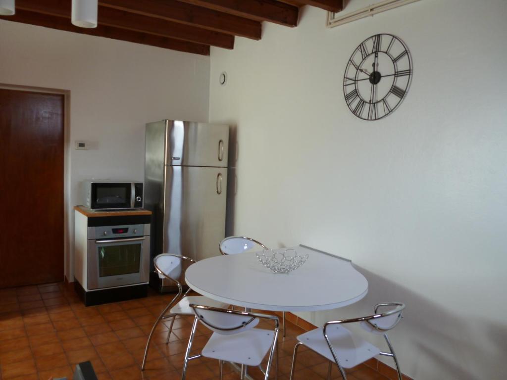 La cuisine est équipée d'une table et de chaises blanches ainsi que d'un réfrigérateur. dans l'établissement Les Sureaux Le Gite 3 étoiles par CDT24, à Le Pizou