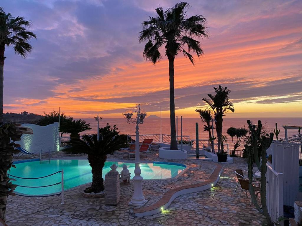 une piscine avec des palmiers et un coucher de soleil dans l'établissement Mediterranean Boutique Hotel, à Tropea