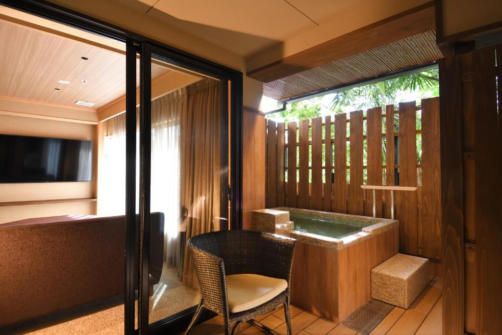 d'un balcon avec une baignoire, une table et une chaise. dans l'établissement Yumotokan, à Ōtsu
