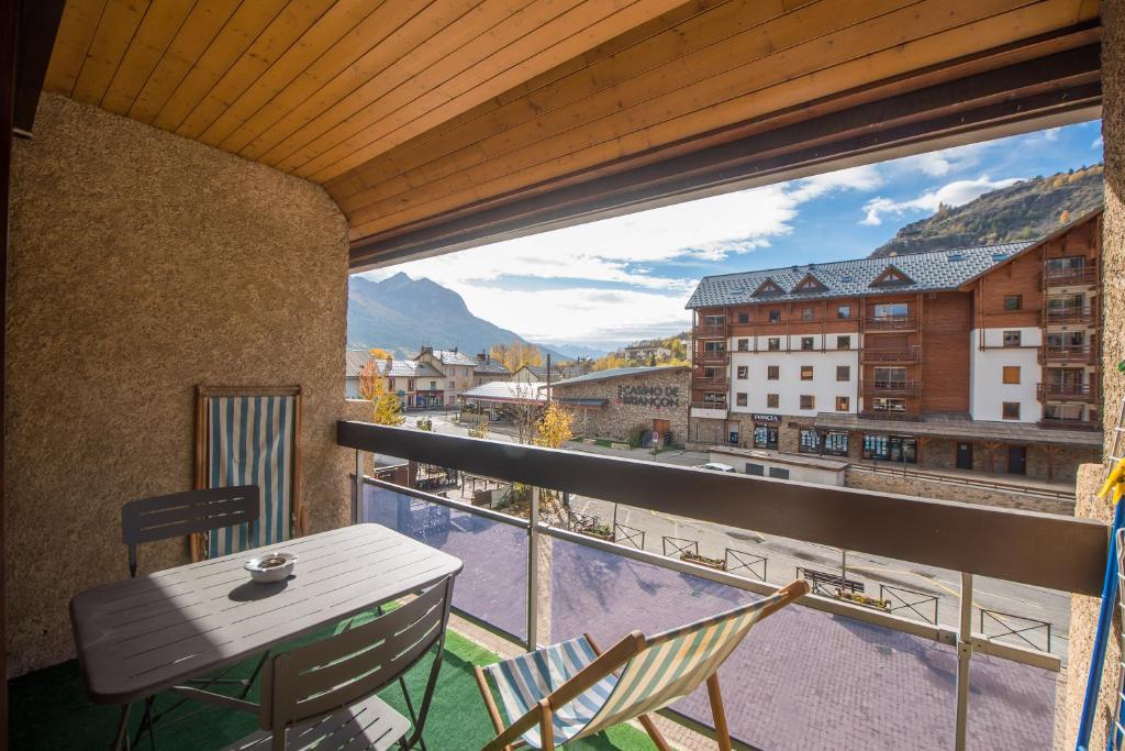 un balcon avec une table et des chaises et une vue dans l'établissement Serre-chevalier Vallée - Briançon, à Briançon