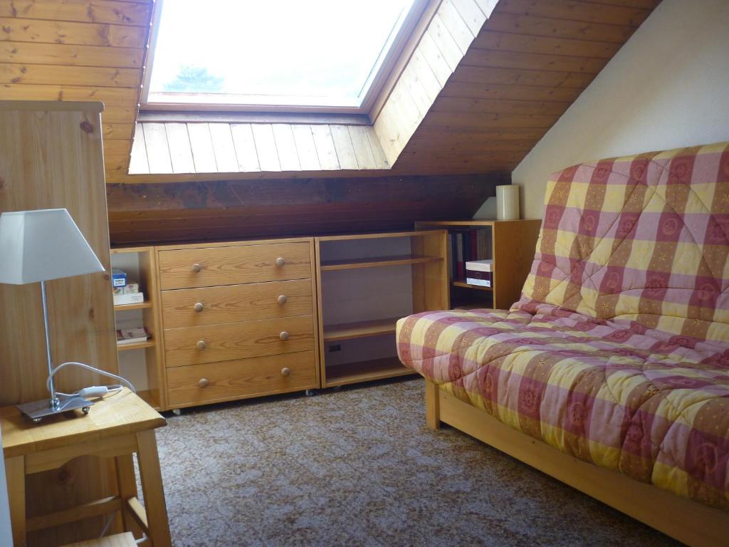 - une chambre mansardée avec un lit et une lucarne dans l'établissement Serre-chevalier Vallée - Briançon, à Briançon