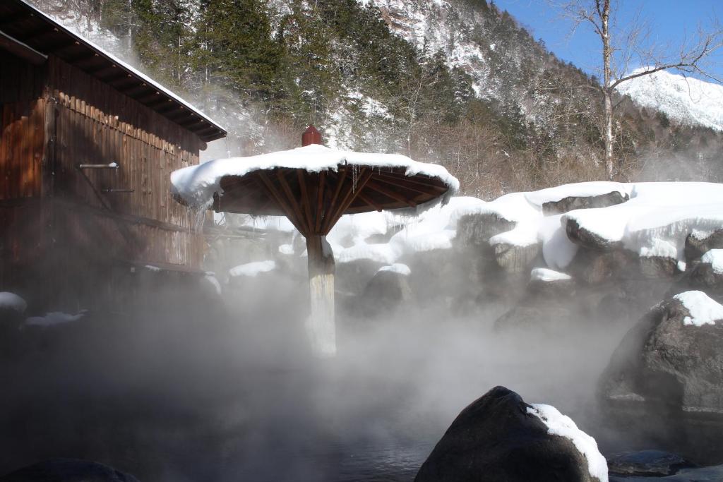 un parapluie dans l'eau avec de la neige dans l'établissement Shinzanso, à Takayama