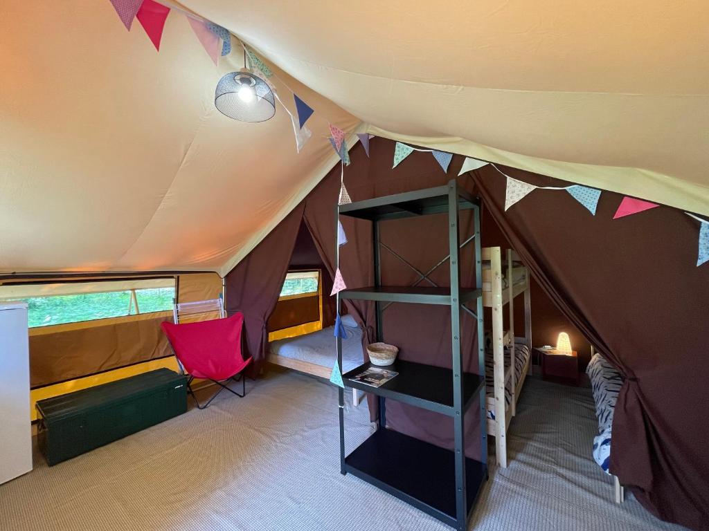 Cette chambre comprend une tente avec une table et une chaise. dans l'établissement Tente Lodge Bouleau - La Téouleyre, à Saint-Julien-en-Born