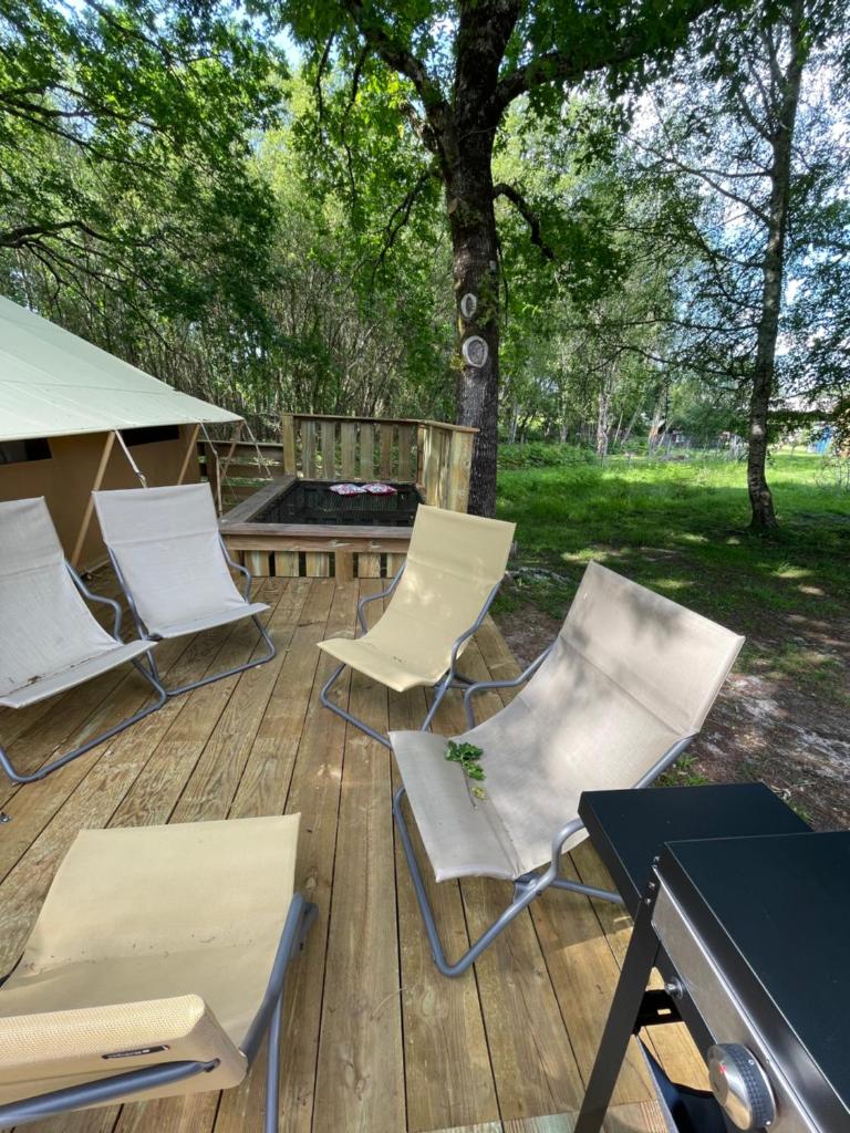 une terrasse avec des chaises, une table et un grill dans l'établissement Tente Lodge Bouleau - La Téouleyre, à Saint-Julien-en-Born