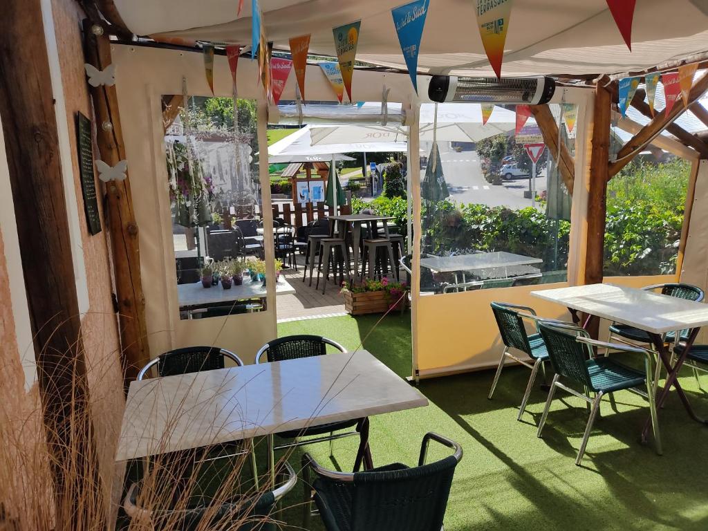 un patio extérieur avec tables, chaises et parasols dans l'établissement Les Fauvettes, à Saint-Léger-les-Mélèzes