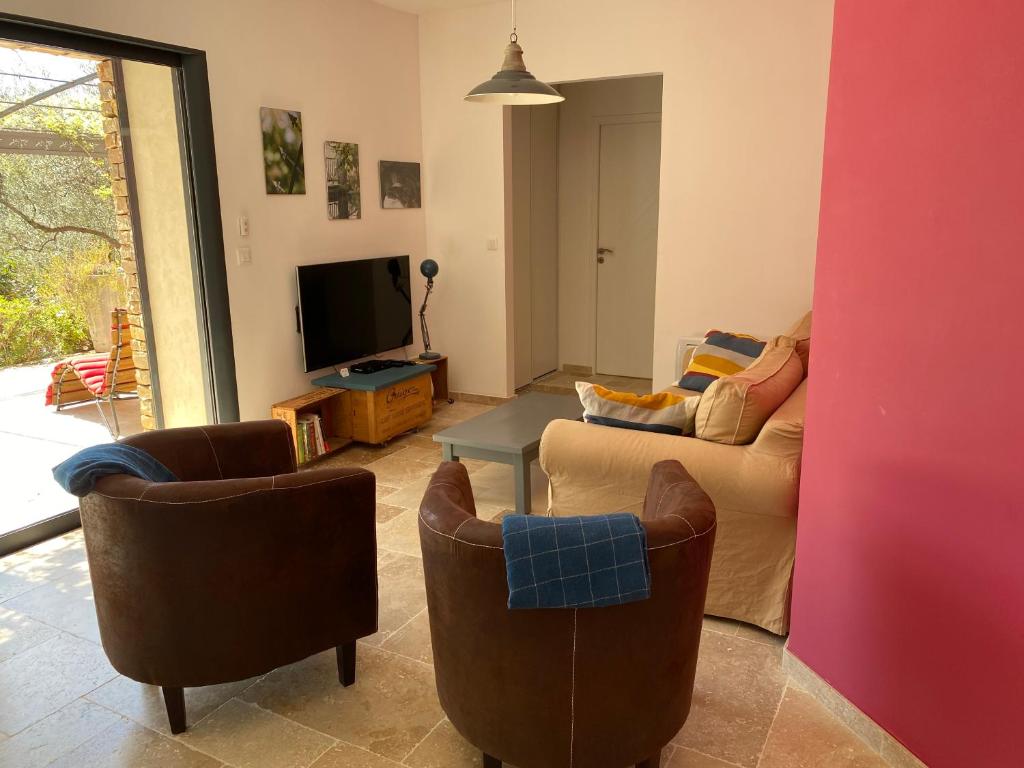 un salon avec un canapé, des chaises et une télévision dans l'établissement gîte de Jo et Chantal, à Belgentier