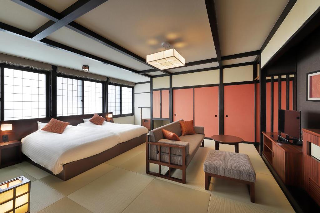 une chambre avec un lit, un canapé et une télévision dans l'établissement Zao Onsen Omiya Ryokan, à Zao Onsen