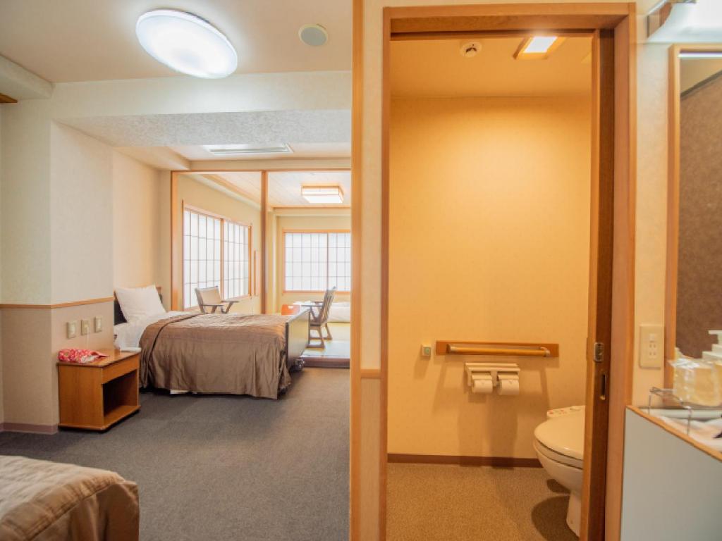 une chambre d'hôtel avec un lit et une salle de bain dans l'établissement Ryokan Hakura, à Yamanouchi