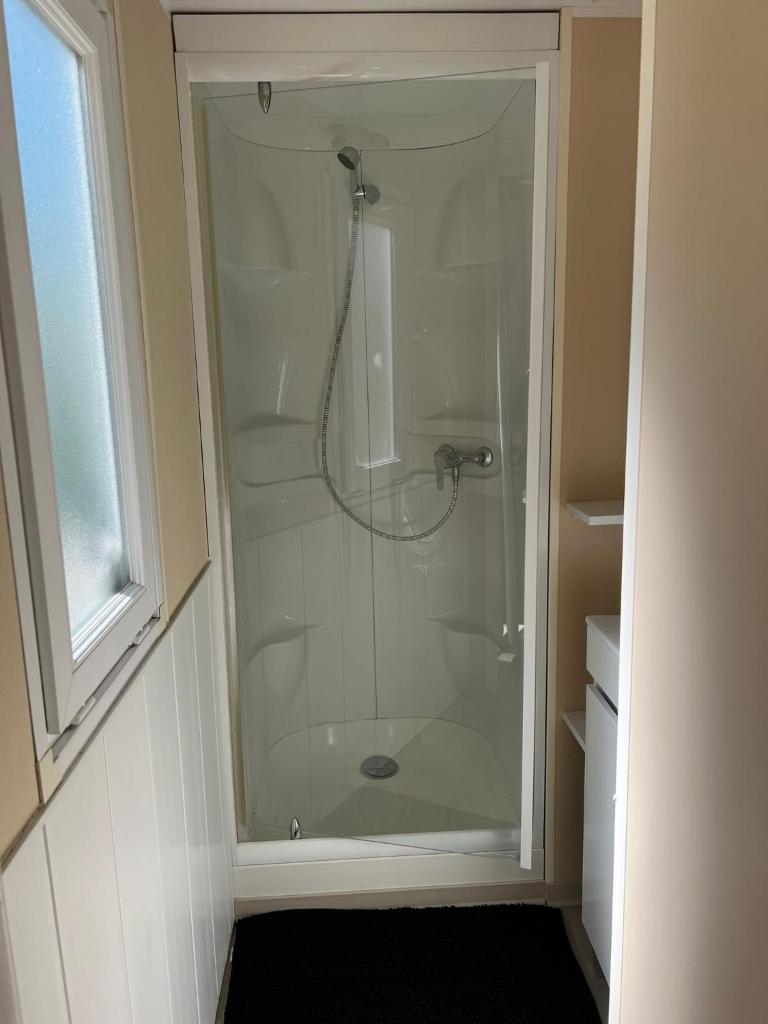 une douche avec une porte vitrée dans une salle de bain dans l'établissement Mobil-Home des Iscles, à La Roque-dʼAnthéron