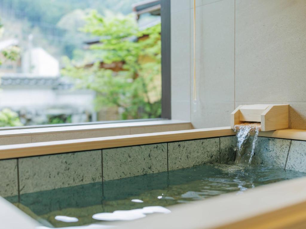 une baignoire avec une fontaine dans l'établissement Ryokan Kigusuriya, à Nantan city