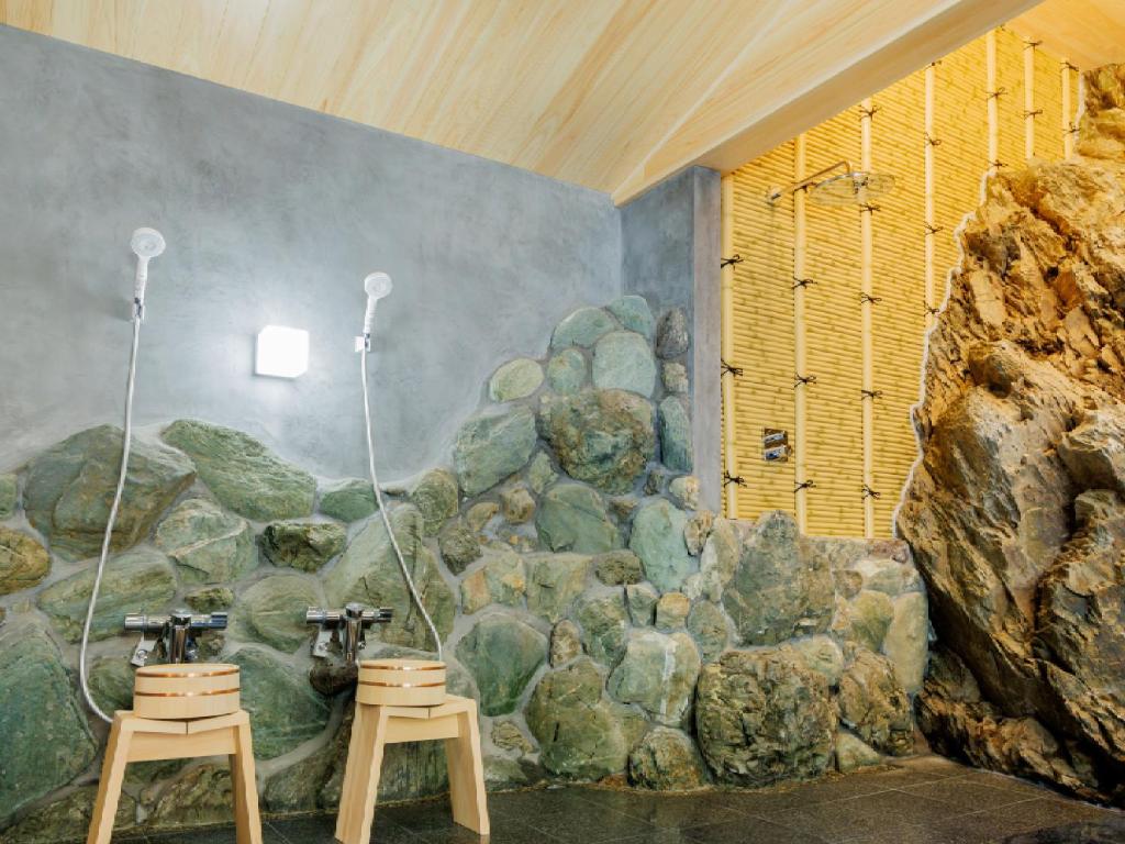 une chambre avec deux tabourets et un mur en pierre dans l'établissement Ryokan Kigusuriya, à Nantan city