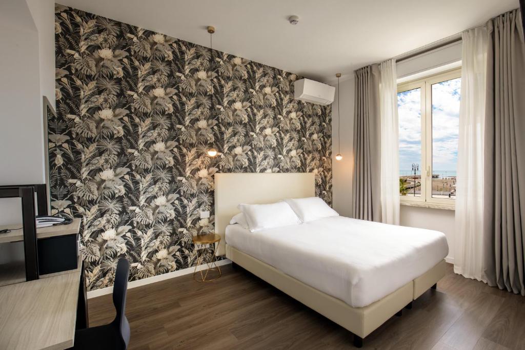 - une chambre avec un lit et un papier peint floral dans l'établissement Hotel La Scaletta, à Lido di Ostia