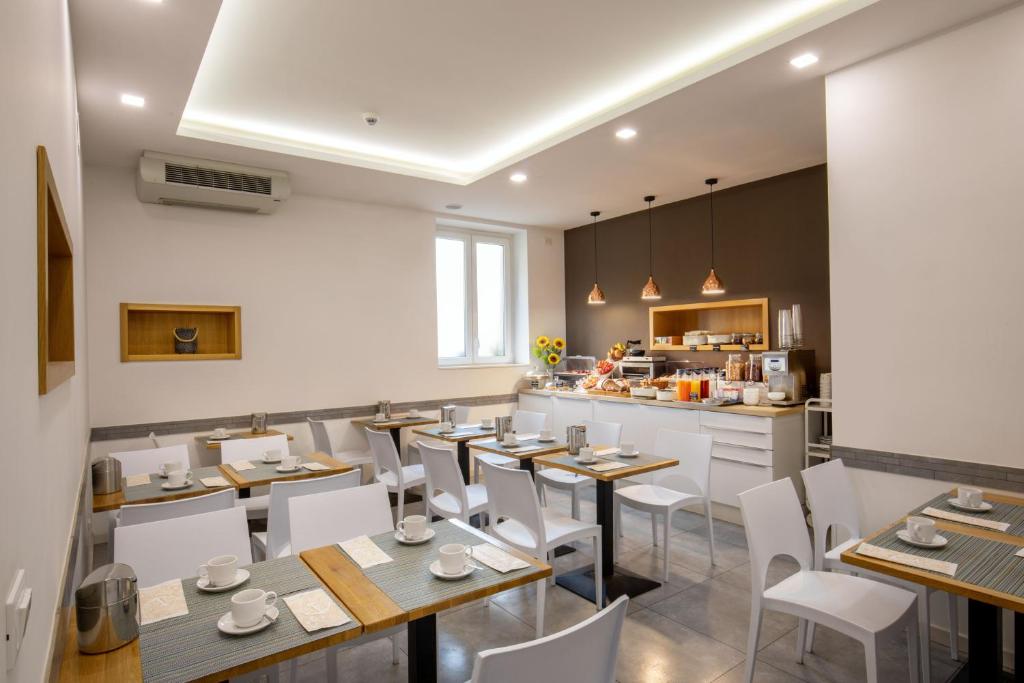 un restaurant avec des tables et des chaises blanches ainsi qu'une cuisine dans l'établissement Hotel La Scaletta, à Lido di Ostia