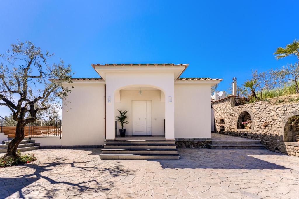 une maison blanche avec une porte et des escaliers blancs dans l'établissement Villa Rusinella Minimalist Retreat with Sea Views by Feeling Italy, à Massa Lubrense