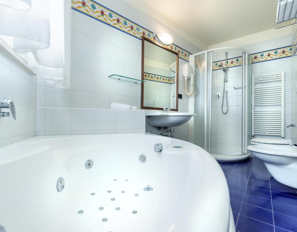 une salle de bain blanche avec une baignoire et un lavabo dans l'établissement Hotel Bellevue Beach - sul mare, à Milano Marittima
