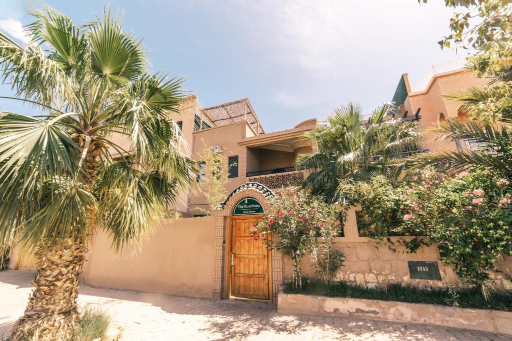 une maison avec une porte en bois et des palmiers dans l'établissement The Kozyhome, à Ouarzazate