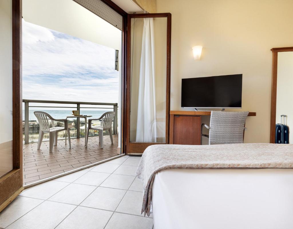 - une chambre avec un lit et un balcon avec une télévision dans l'établissement Hotel Bellevue Beach - sul mare, à Milano Marittima