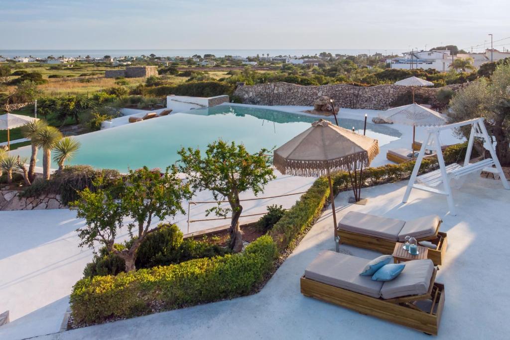 - une vue sur la piscine et ses 2 chaises longues dans l'établissement Masseria Samenti, à Torre Suda