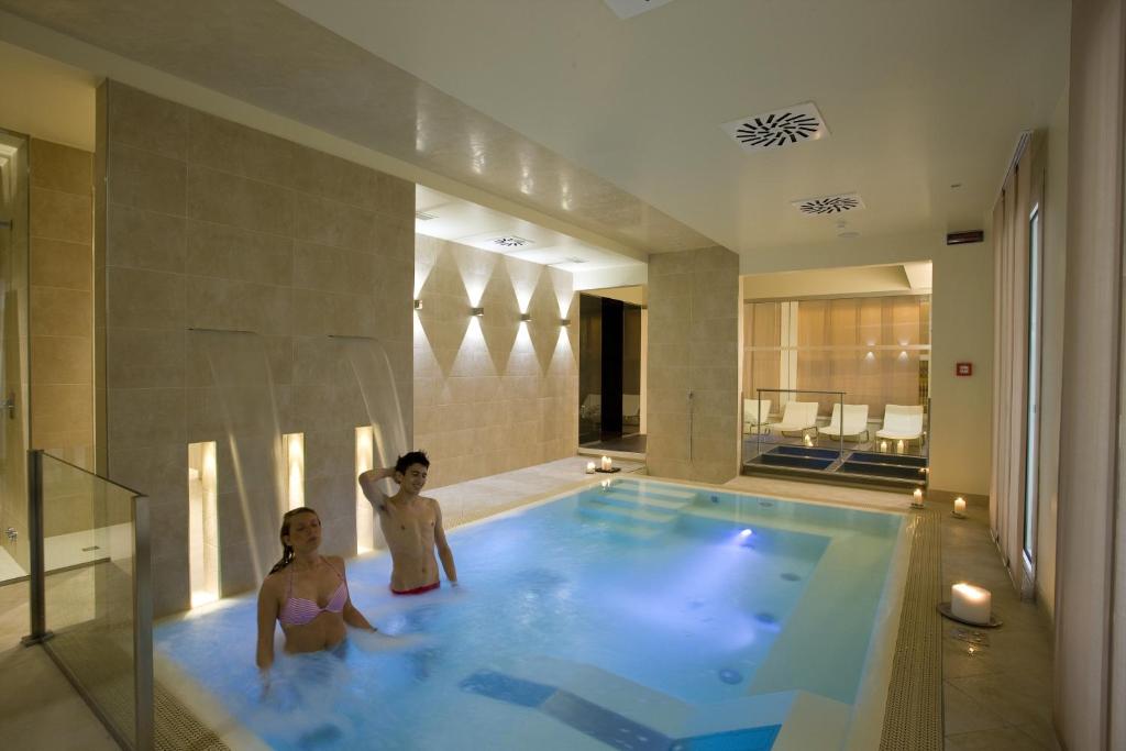 un homme et une femme dans une piscine dans l'établissement Hotel Consuelo, à Riccione