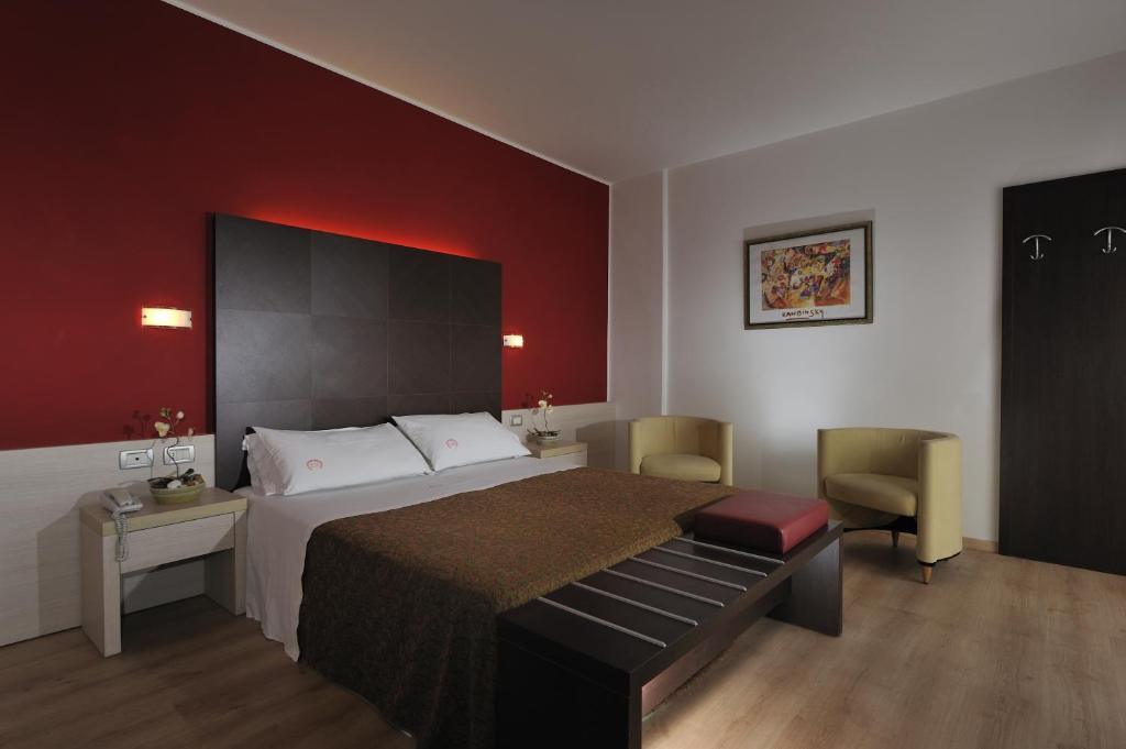 une chambre avec un grand lit et un mur rouge dans l'établissement Hotel Eden, à Bibione