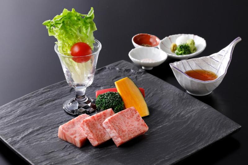 une assiette de denrées alimentaires contenant de la viande et des légumes sur une table dans l'établissement Ryokusuitei, à Kamogawa 37 autres photos