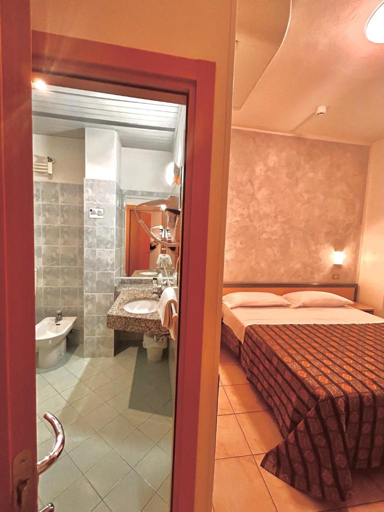 une chambre d'hôtel avec un lit et une salle de bain dans l'établissement Hotel Ausonia, à Milano Marittima
