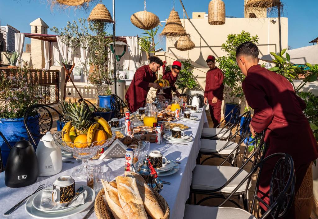un groupe de personnes debout autour d'une table avec de la nourriture dans l'établissement Riad Dar El Médina - Heated Swimming pool, jacuzzi & Spa, à Marrakech