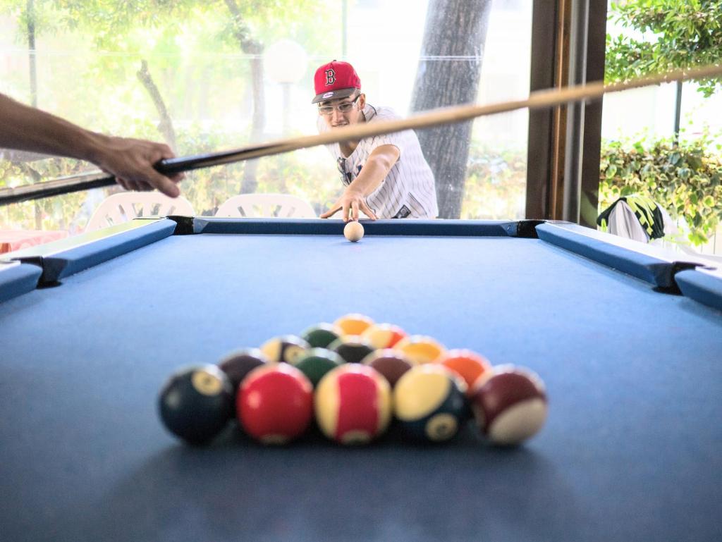 un homme jouant au billard avec un guide dans l'établissement Hotel Apis, à Rimini