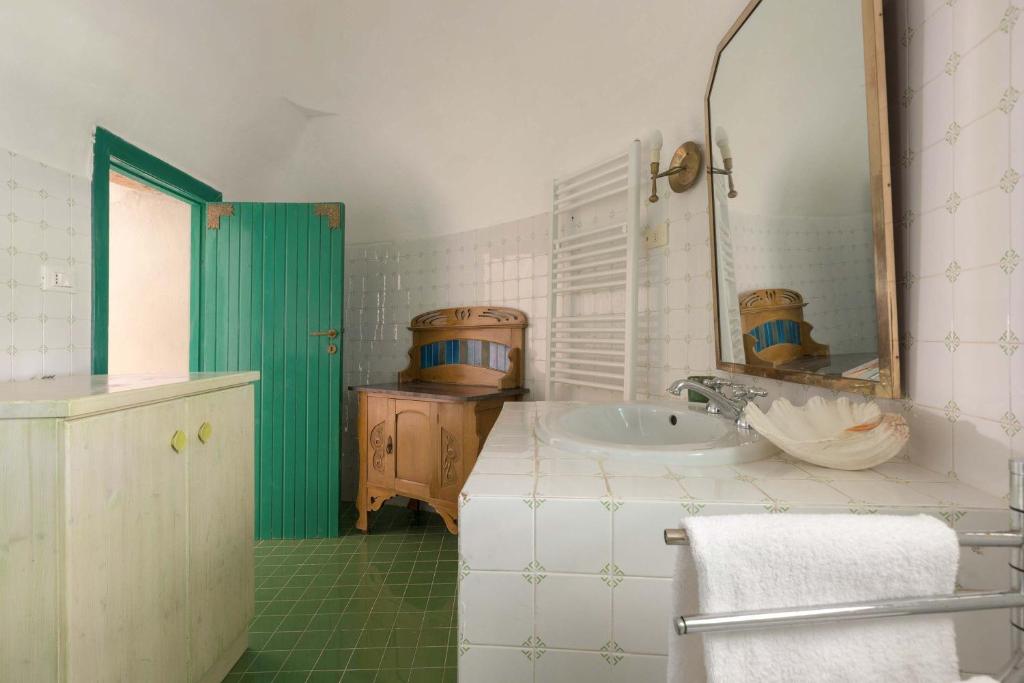 une salle de bain avec un lavabo et un miroir dans l'établissement Trulli Il Cappero by Perle di Puglia, à Ostuni
