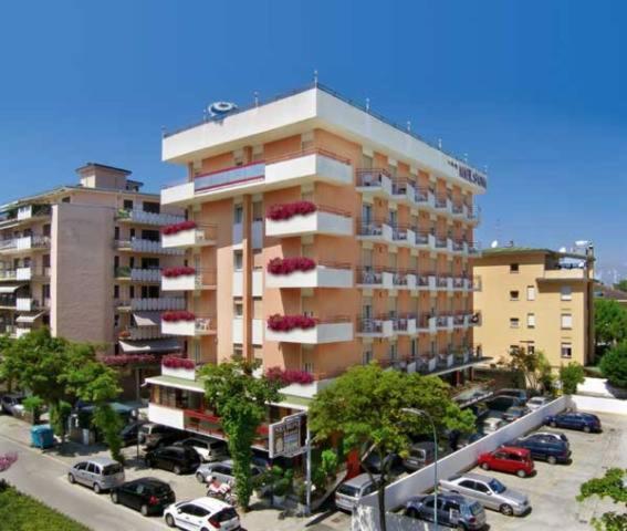 un grand bâtiment avec des voitures garées dans un parking dans l'établissement Hotel Nelson, à Lido di Jesolo