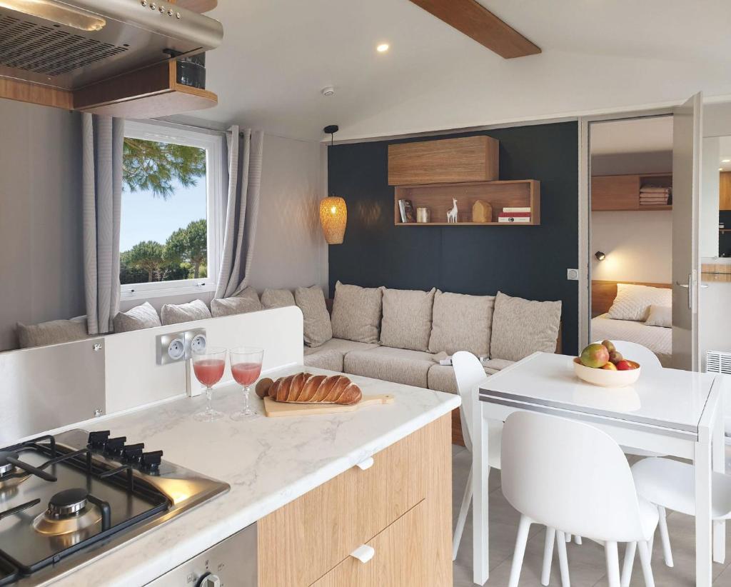 une cuisine et un salon avec un canapé et une table dans l'établissement Le Bungalow du Ferret - Mobil Home Premium avec vue bassin d'Arcachon, à Claouey 5 autres photos
