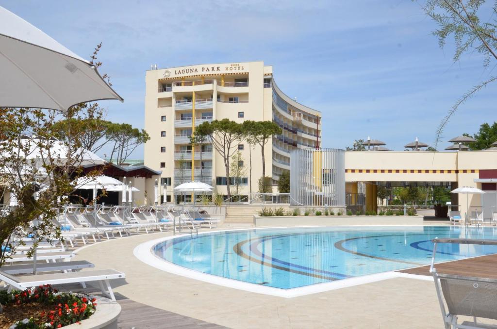 une piscine dans un hôtel avec des chaises et un bâtiment dans l'établissement Laguna Park Hotel 4Superior, à Bibione