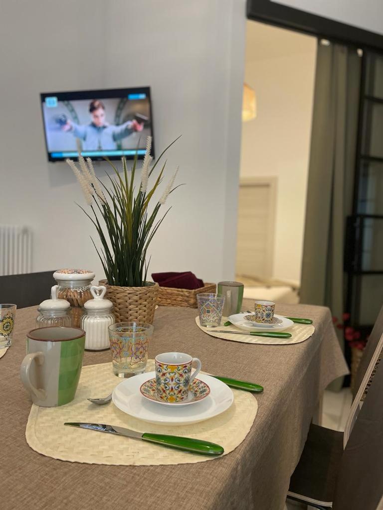 une table avec des assiettes et des tasses et une télévision dans une pièce dans l'établissement Maioliche Apartment, à Margherita di Savoia