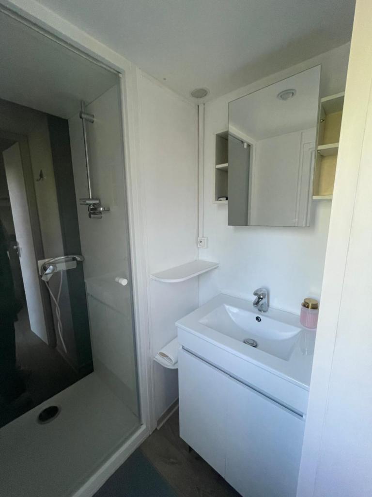 une salle de bain blanche avec un lavabo et une douche dans l'établissement Mobil-Home au pied du Luberon, à La Roque-dʼAnthéron