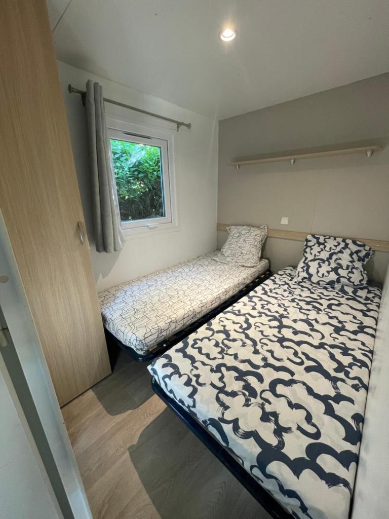 une chambre avec deux lits et une fenêtre dans l'établissement Mobil-Home au pied du Luberon, à La Roque-dʼAnthéron