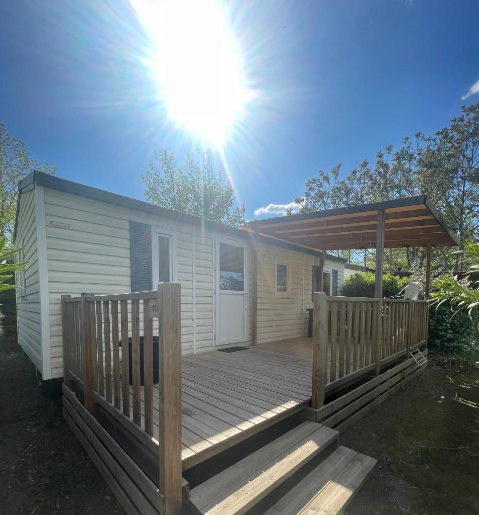 une maison avec une terrasse avec le soleil dans le ciel dans l'établissement Mobil-Home au pied du Luberon, à La Roque-dʼAnthéron