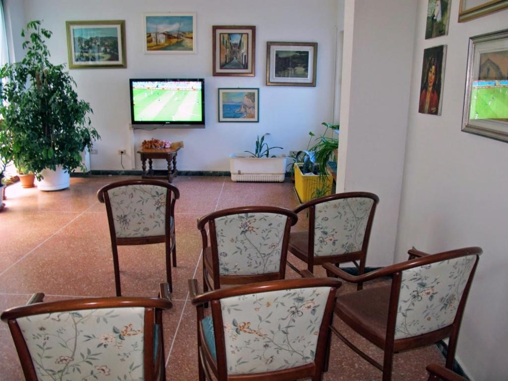 Cette chambre dispose de chaises et d'une télévision à écran plat. dans l'établissement Hotel Capo Noli, à Noli