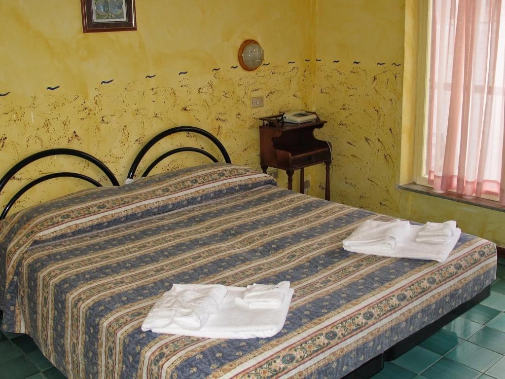 une chambre avec un lit avec des serviettes dessus dans l'établissement Hotel Capo Noli, à Noli