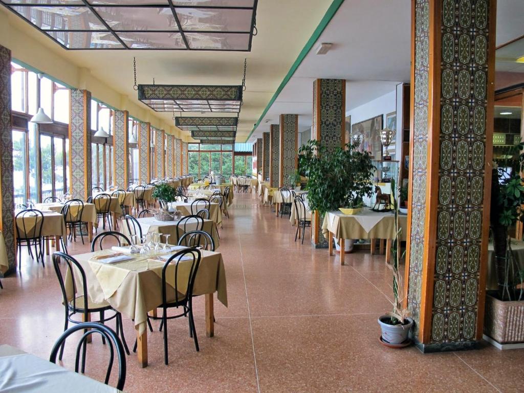 une salle à manger avec tables, chaises et fenêtres dans l'établissement Hotel Capo Noli, à Noli