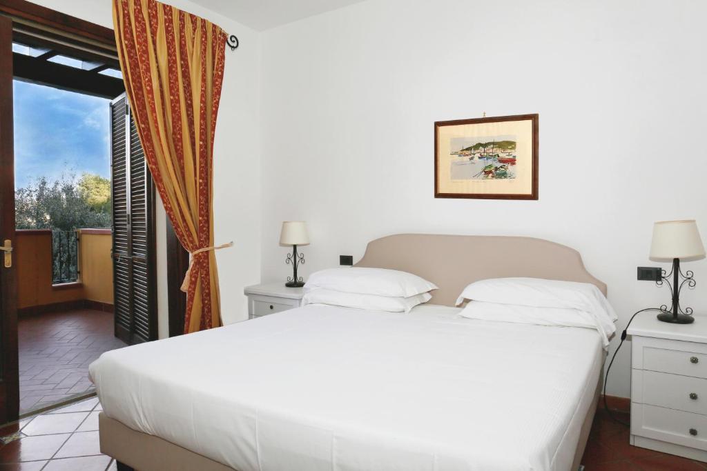 une chambre avec un grand lit blanc et une fenêtre dans l'établissement Albergo Filippo II, à Porto Santo Stefano 45 autres photos