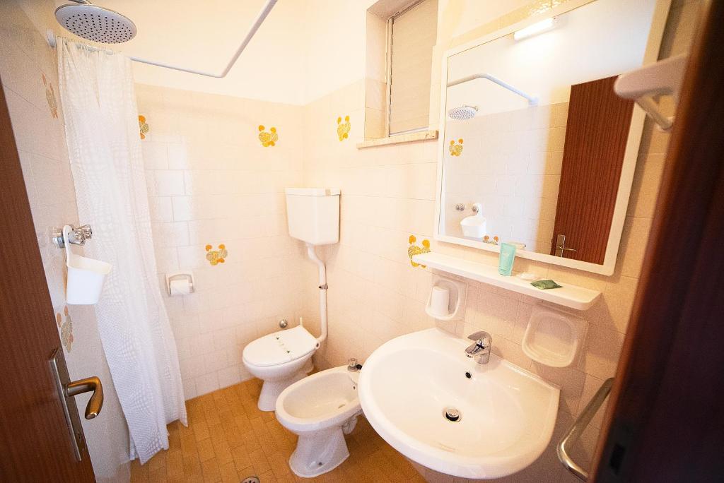 une salle de bain avec un lavabo, des toilettes et un miroir dans l'établissement Hotel Ischia, à Rimini