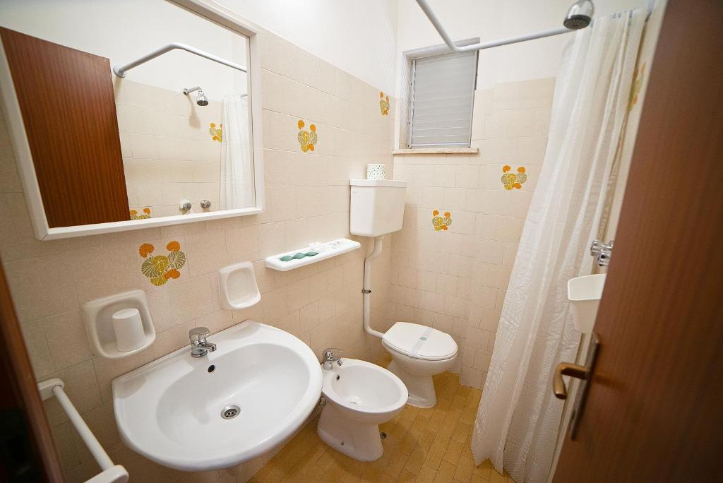 une salle de bain avec un lavabo, des toilettes et un miroir dans l'établissement Hotel Ischia, à Rimini 64 autres photos
