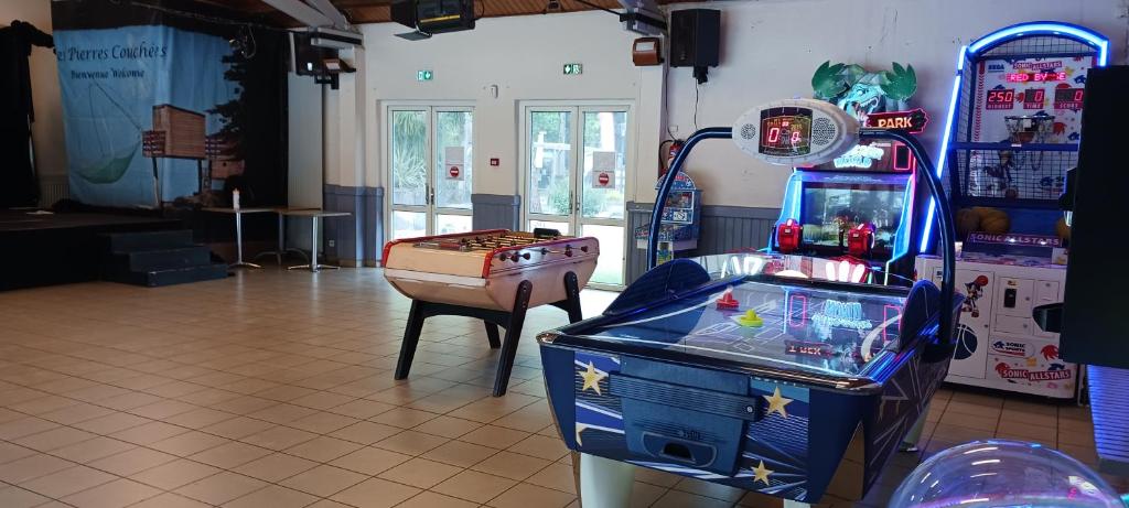 une chambre avec une machine de jeux vidéo et une table dans l'établissement Mobil home 4-6 places St brėvin les pins 44, à Saint-Brévin-les-Pins