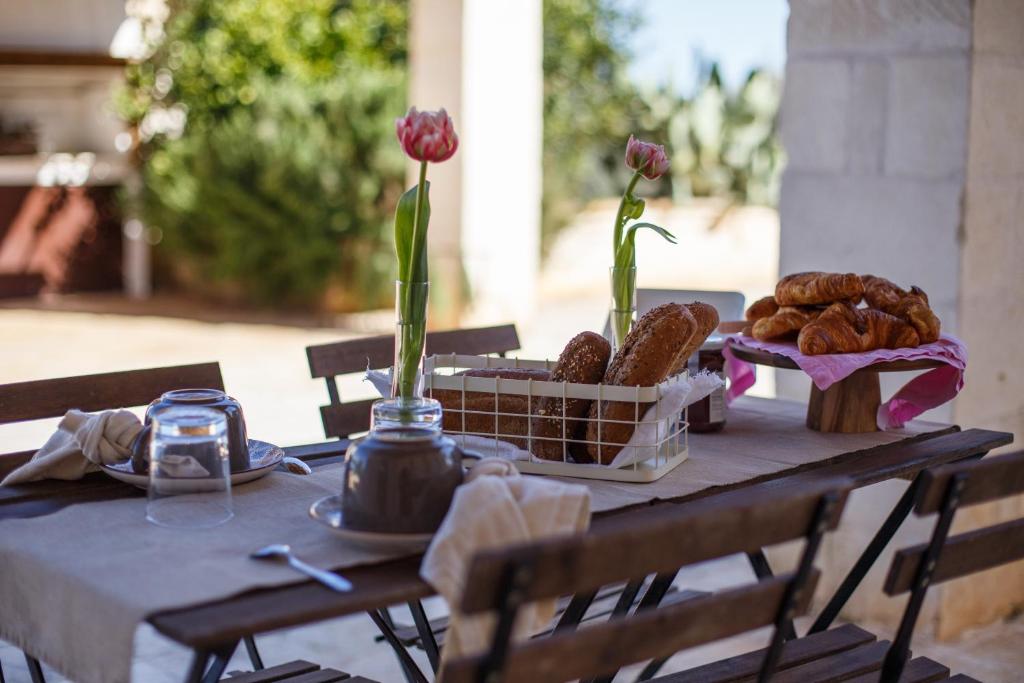 une table avec un panier de pâtisseries et de fleurs dessus dans l'établissement Antica Pietra - Villa con piscina in Puglia, à Ostuni